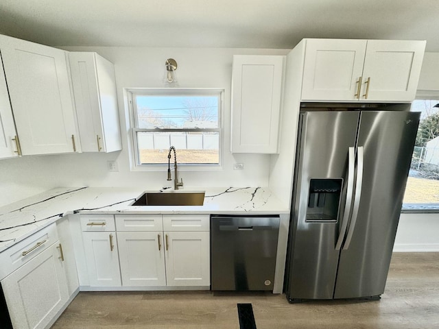 kitchen with dishwashing machine, sink, white cabinetry, and stainless steel fridge