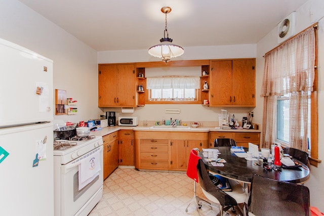 kitchen with hanging light fixtures, white appliances, and sink