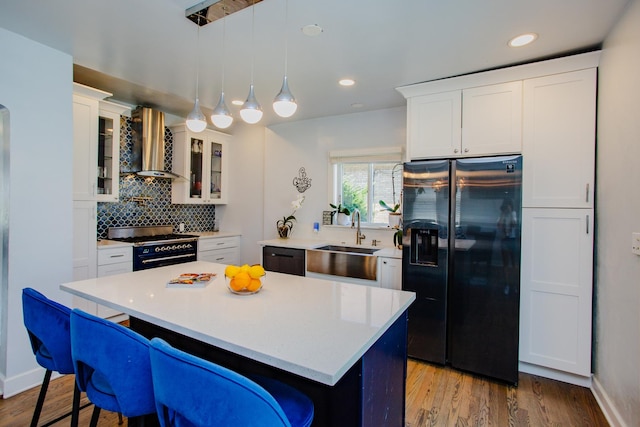 kitchen featuring white cabinets, sink, wall chimney exhaust hood, and black appliances