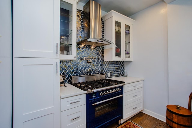 kitchen featuring dark hardwood / wood-style floors, range with gas cooktop, white cabinets, decorative backsplash, and wall chimney exhaust hood