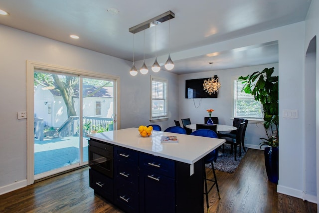 kitchen featuring plenty of natural light, a kitchen breakfast bar, decorative light fixtures, and a kitchen island