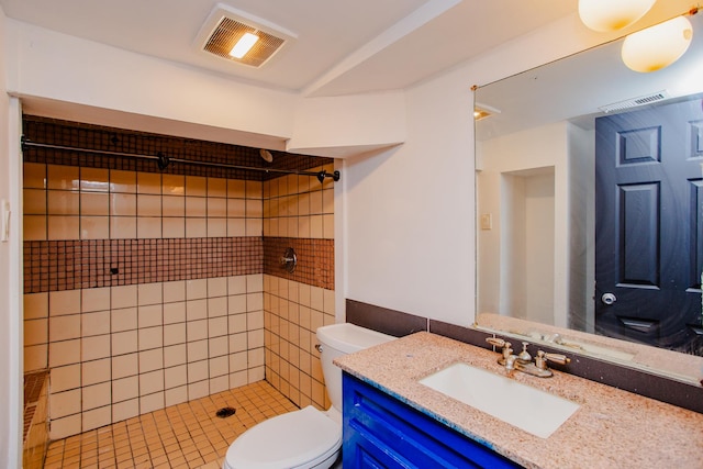 bathroom featuring a tile shower, vanity, and toilet