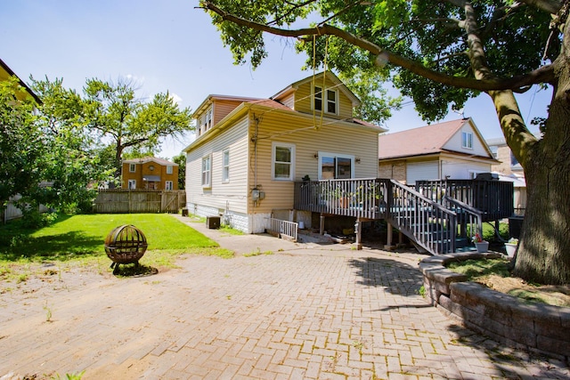 rear view of property with central air condition unit, an outdoor fire pit, a yard, a deck, and a patio