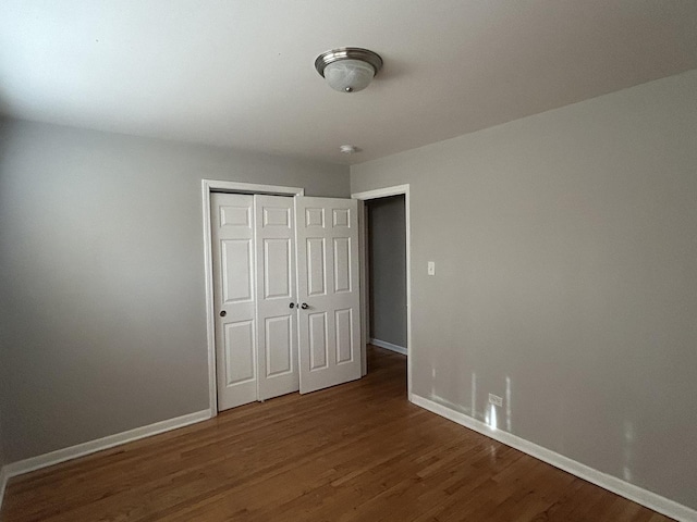 unfurnished bedroom featuring dark hardwood / wood-style flooring and a closet