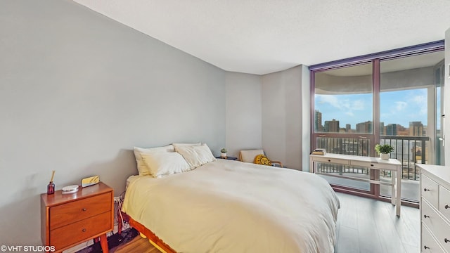 bedroom with expansive windows, access to exterior, a textured ceiling, and light hardwood / wood-style flooring