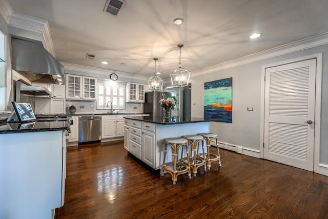 kitchen featuring a kitchen island, pendant lighting, stainless steel appliances, range hood, and white cabinets