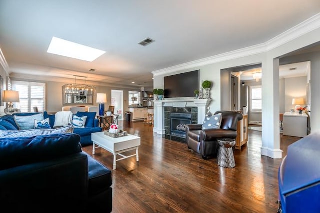 living room with crown molding, a fireplace, dark hardwood / wood-style flooring, and a skylight