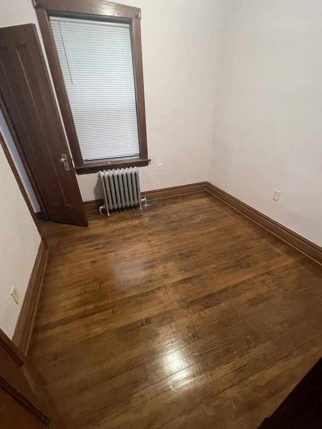 spare room featuring radiator heating unit and dark hardwood / wood-style flooring