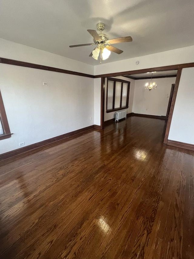 empty room with radiator heating unit, dark hardwood / wood-style floors, and ceiling fan with notable chandelier