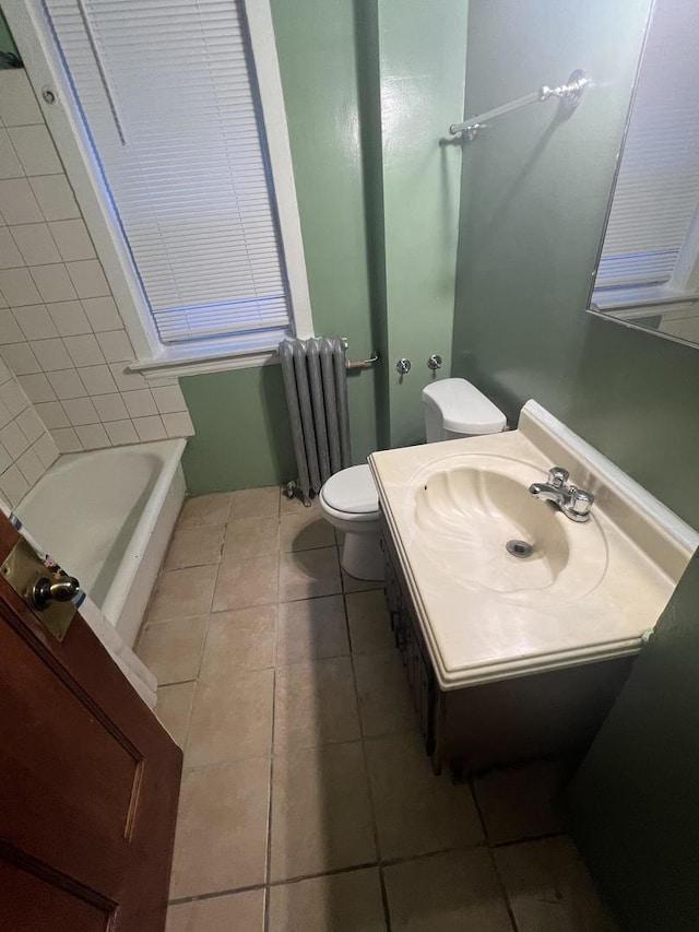 bathroom featuring radiator, a tub to relax in, vanity, toilet, and tile patterned floors