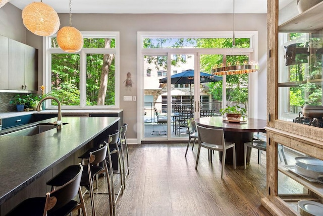 kitchen with pendant lighting, tasteful backsplash, sink, white cabinets, and dark wood-type flooring