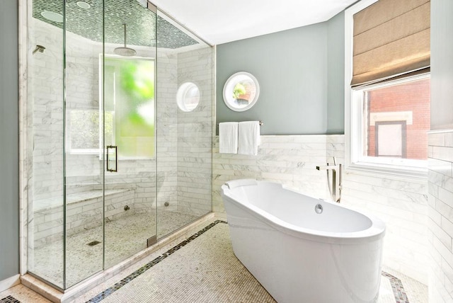 bathroom with shower with separate bathtub and tile walls