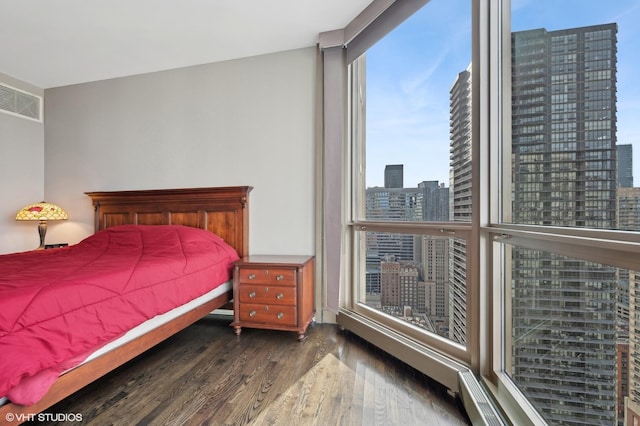 bedroom featuring a wall of windows and dark hardwood / wood-style floors