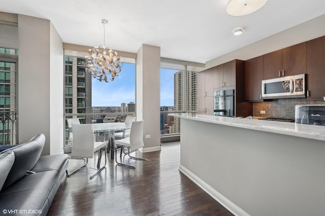 kitchen featuring dark brown cabinetry, decorative light fixtures, appliances with stainless steel finishes, dark hardwood / wood-style floors, and decorative backsplash