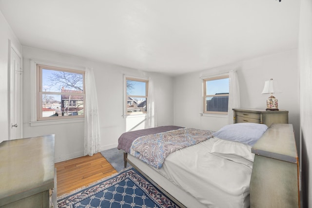 bedroom with multiple windows and hardwood / wood-style flooring