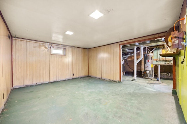 basement with water heater, sink, and wood walls