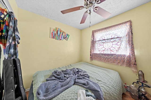 bedroom with ceiling fan, wood-type flooring, and a textured ceiling