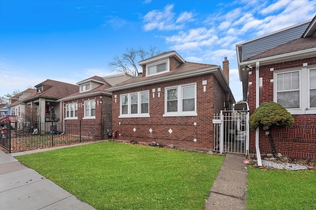 view of front of house with brick siding, a front yard, fence, and a gate