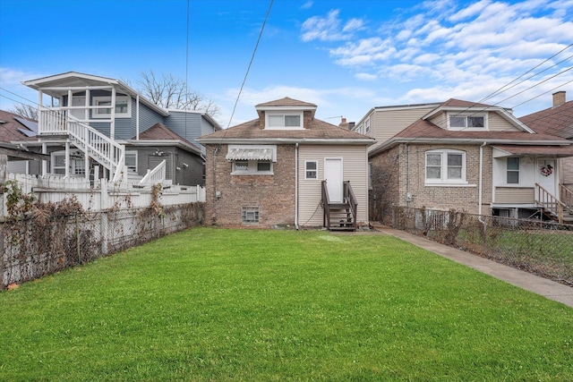 back of property featuring entry steps, fence private yard, a lawn, and brick siding