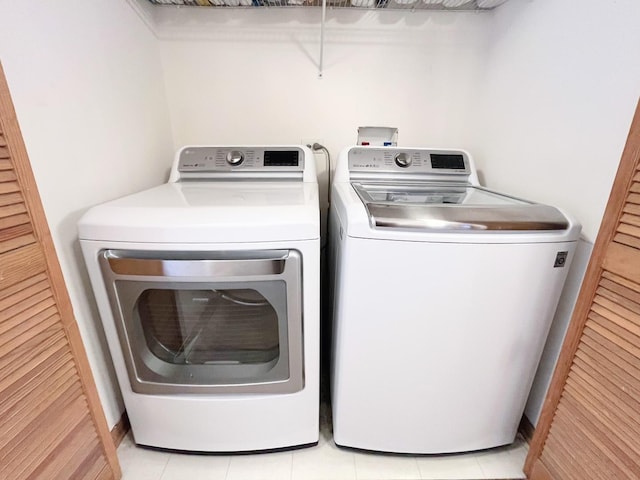 clothes washing area featuring washing machine and clothes dryer and light tile patterned floors