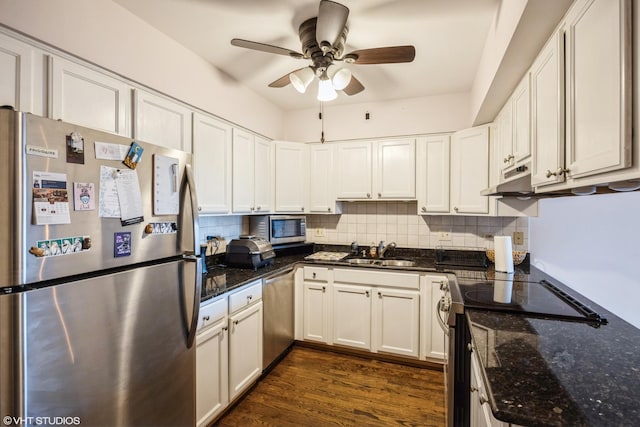 kitchen with tasteful backsplash, white cabinetry, sink, dark stone countertops, and stainless steel appliances