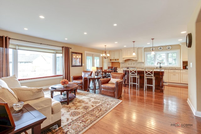 living room with a chandelier, sink, and light hardwood / wood-style flooring