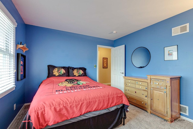 bedroom with multiple windows and light colored carpet