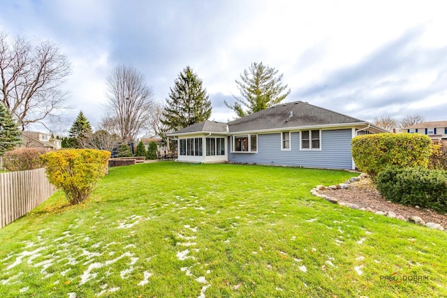 rear view of property with a sunroom and a yard