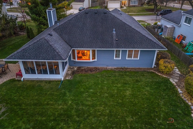 rear view of house with a patio, a sunroom, and a lawn