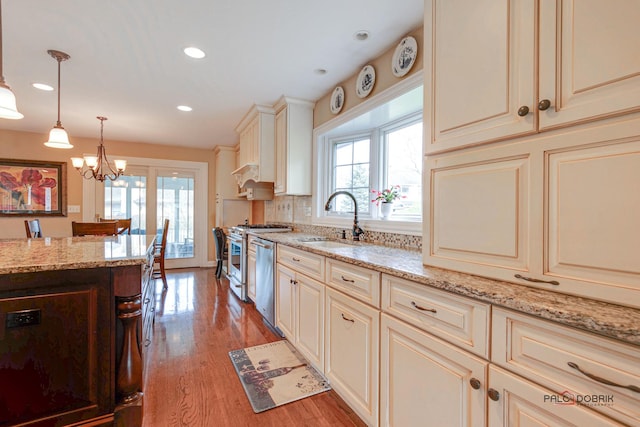 kitchen with a wealth of natural light, pendant lighting, dishwasher, sink, and cream cabinetry