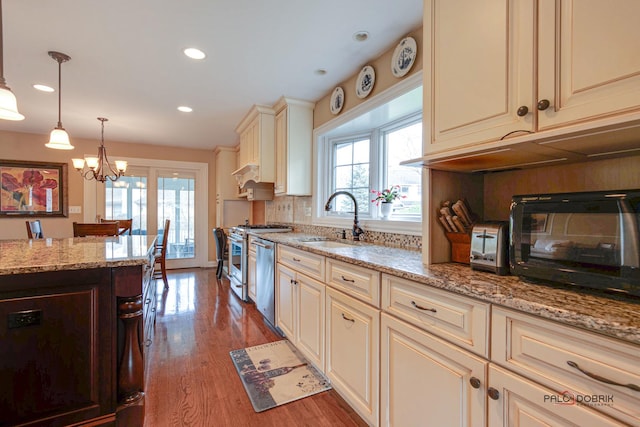 kitchen with plenty of natural light, decorative light fixtures, dishwasher, sink, and cream cabinets