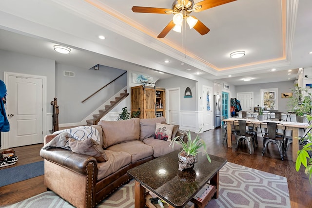 living room featuring ornamental molding, ceiling fan, dark hardwood / wood-style flooring, and a tray ceiling