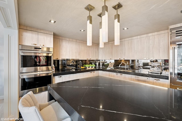 kitchen with double oven, decorative light fixtures, tasteful backsplash, dark stone countertops, and light brown cabinets