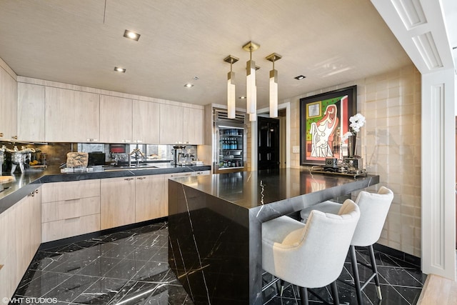 kitchen featuring decorative backsplash, a kitchen breakfast bar, decorative light fixtures, and light brown cabinetry