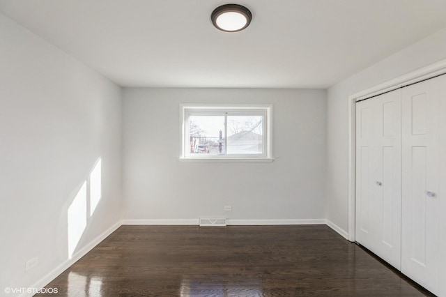 unfurnished bedroom featuring dark hardwood / wood-style flooring and a closet