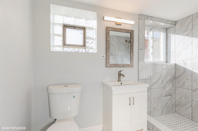 bathroom with vanity, toilet, and tiled shower