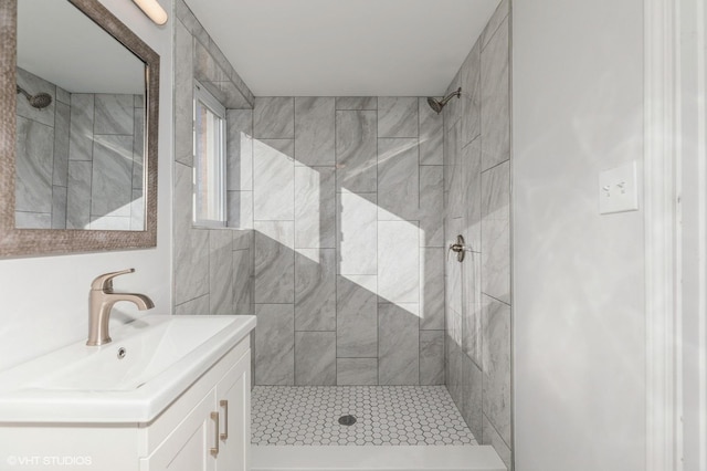 bathroom with tiled shower and vanity