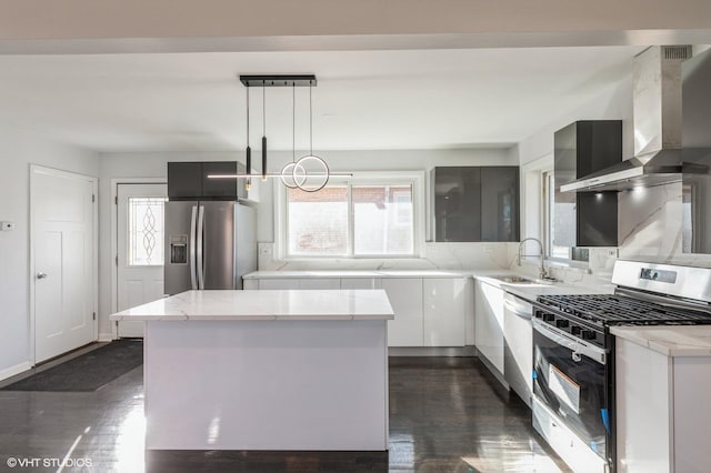 kitchen featuring wall chimney range hood, white cabinetry, stainless steel appliances, light stone counters, and decorative light fixtures