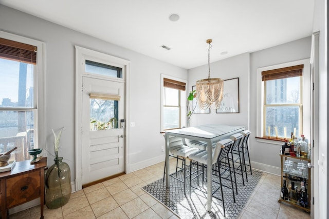 tiled dining room with a chandelier