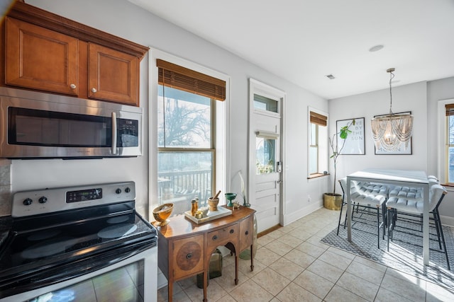 kitchen with appliances with stainless steel finishes, a chandelier, hanging light fixtures, and light tile patterned floors