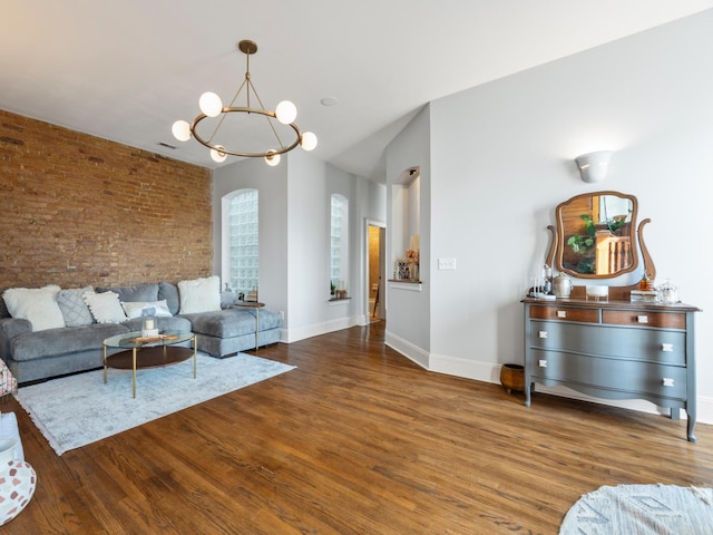 living room with brick wall, a notable chandelier, and dark hardwood / wood-style flooring