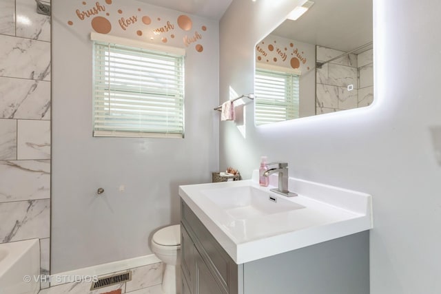 full bathroom with vanity, tiled shower / bath combo, and toilet