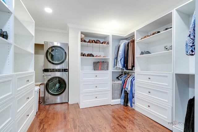 clothes washing area with hardwood / wood-style flooring, stacked washing maching and dryer, and ornamental molding