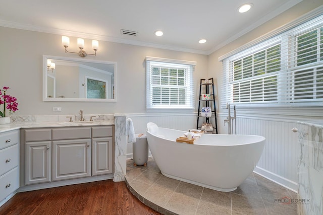 bathroom with hardwood / wood-style floors, crown molding, a washtub, and vanity