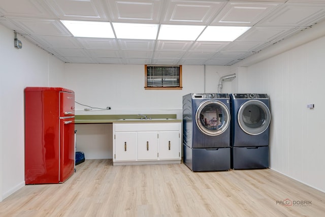 laundry area with cabinets, washing machine and dryer, sink, and light hardwood / wood-style flooring