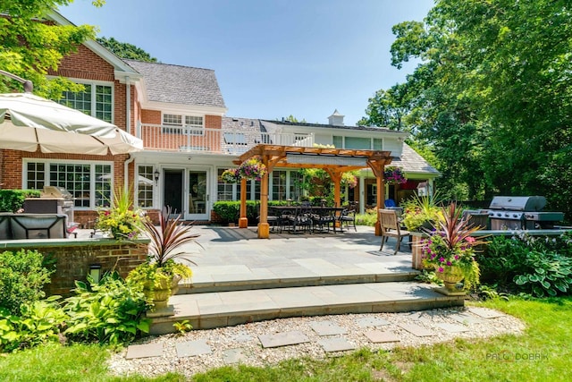 rear view of property featuring french doors, a balcony, a pergola, and a patio