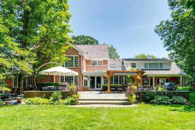 rear view of house with a balcony, a jacuzzi, and a lawn