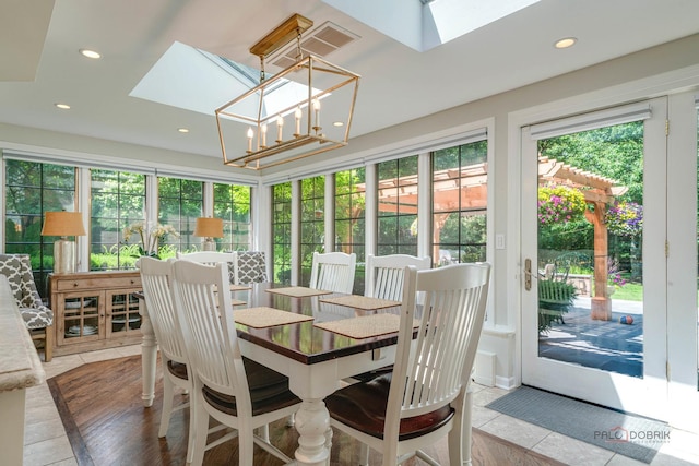 tiled dining area featuring a notable chandelier and a skylight