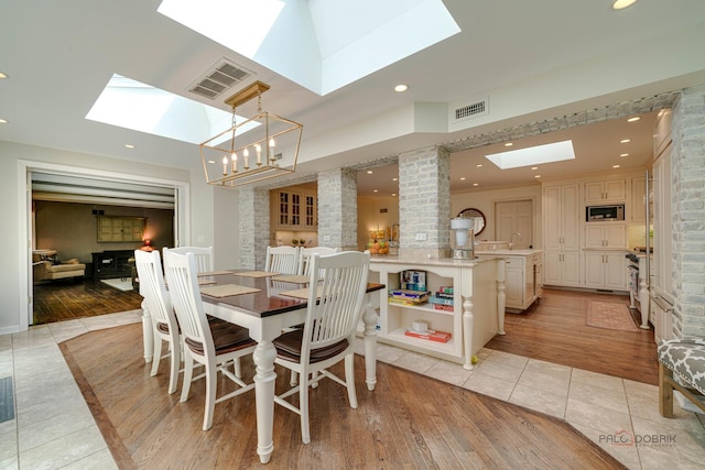 tiled dining room featuring sink, a skylight, and decorative columns