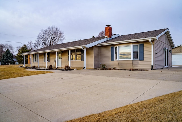 single story home featuring a porch, a garage, and a front yard